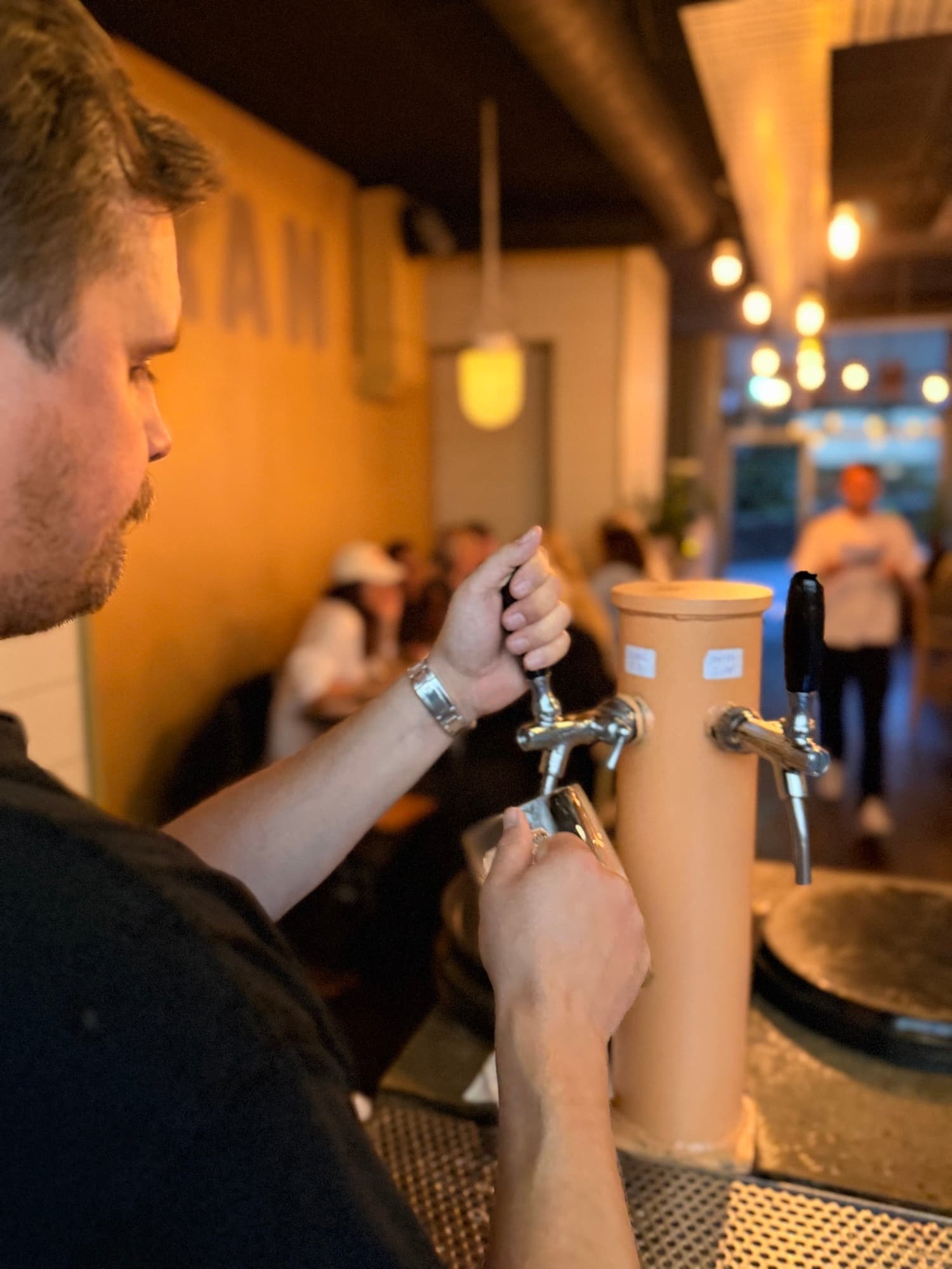 Bartender som tappar upp öl ur ett korallfärgat tapptorn