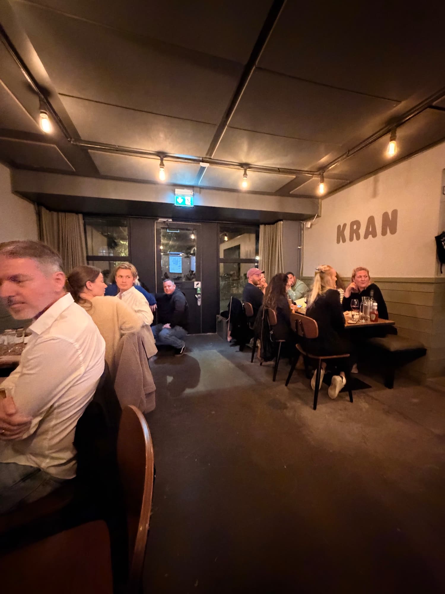 Matsalen på Kran en kväll, gäster vid borden och KRAN på väggen