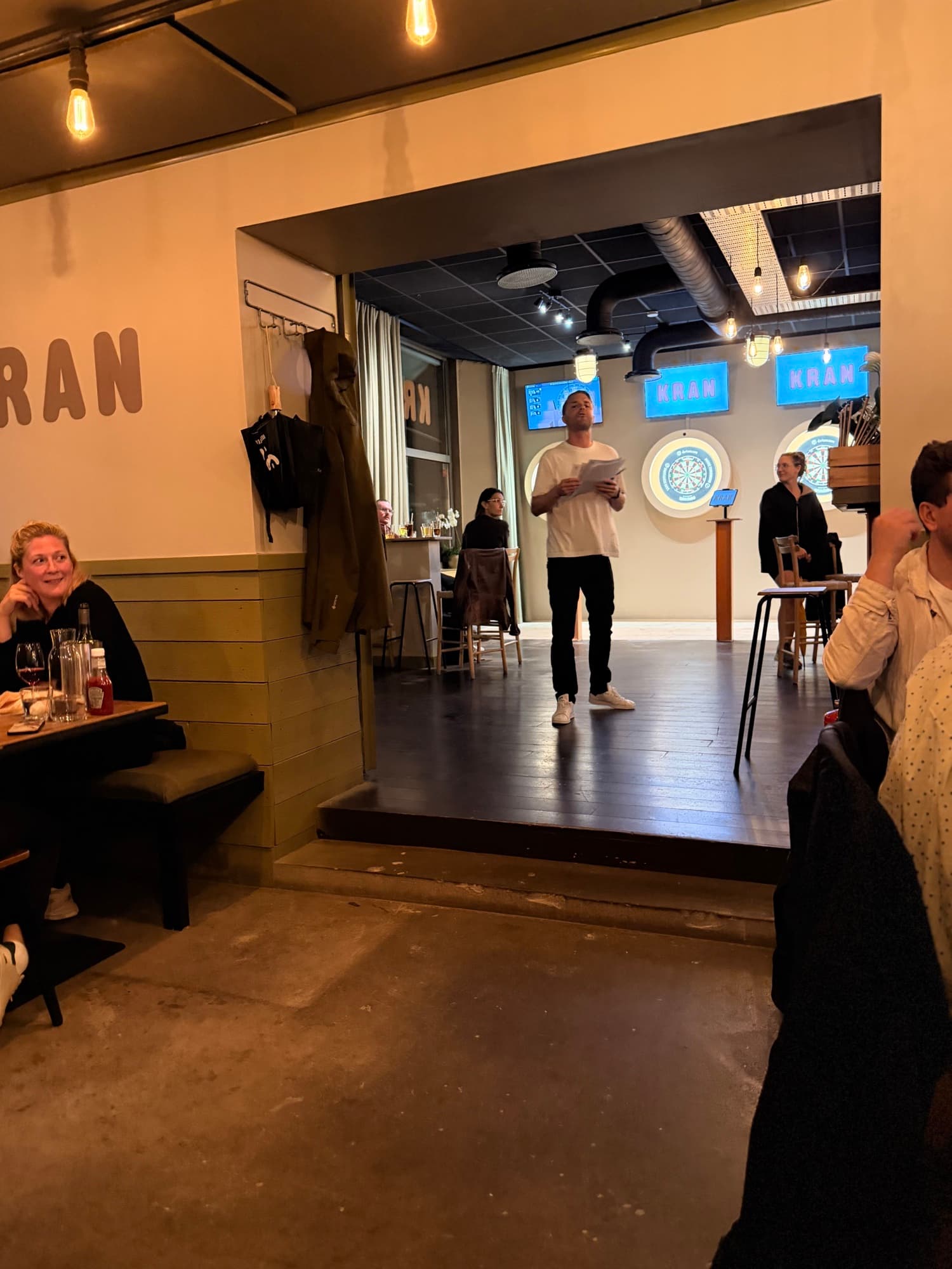 The quiz host reading the questions in front of the darts room and the KRAN signs