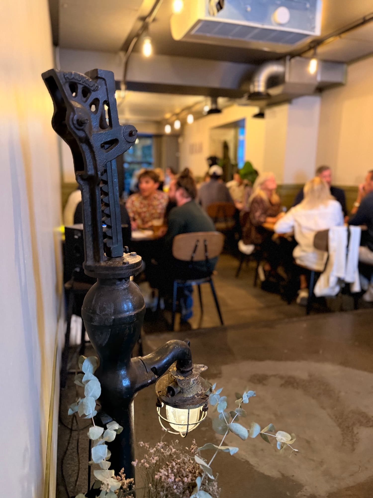 The old cast-iron water pump in the foreground with guests at the tables behind